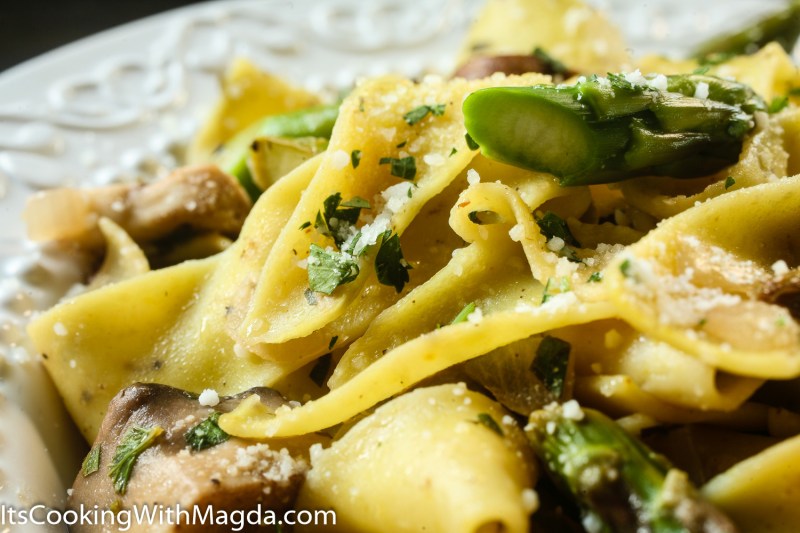 mushroom asparagus pasta on a white plate with grated parmesan cheese