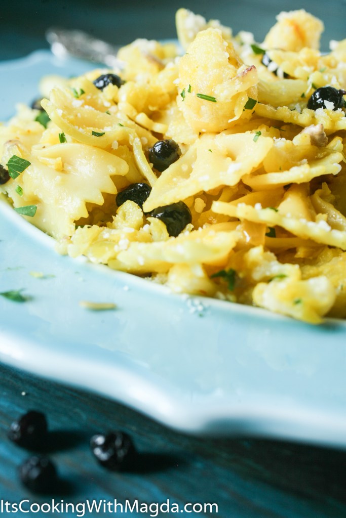Pasta with cauliflower, dried blueberries, parmesan cheese on a blue plate
