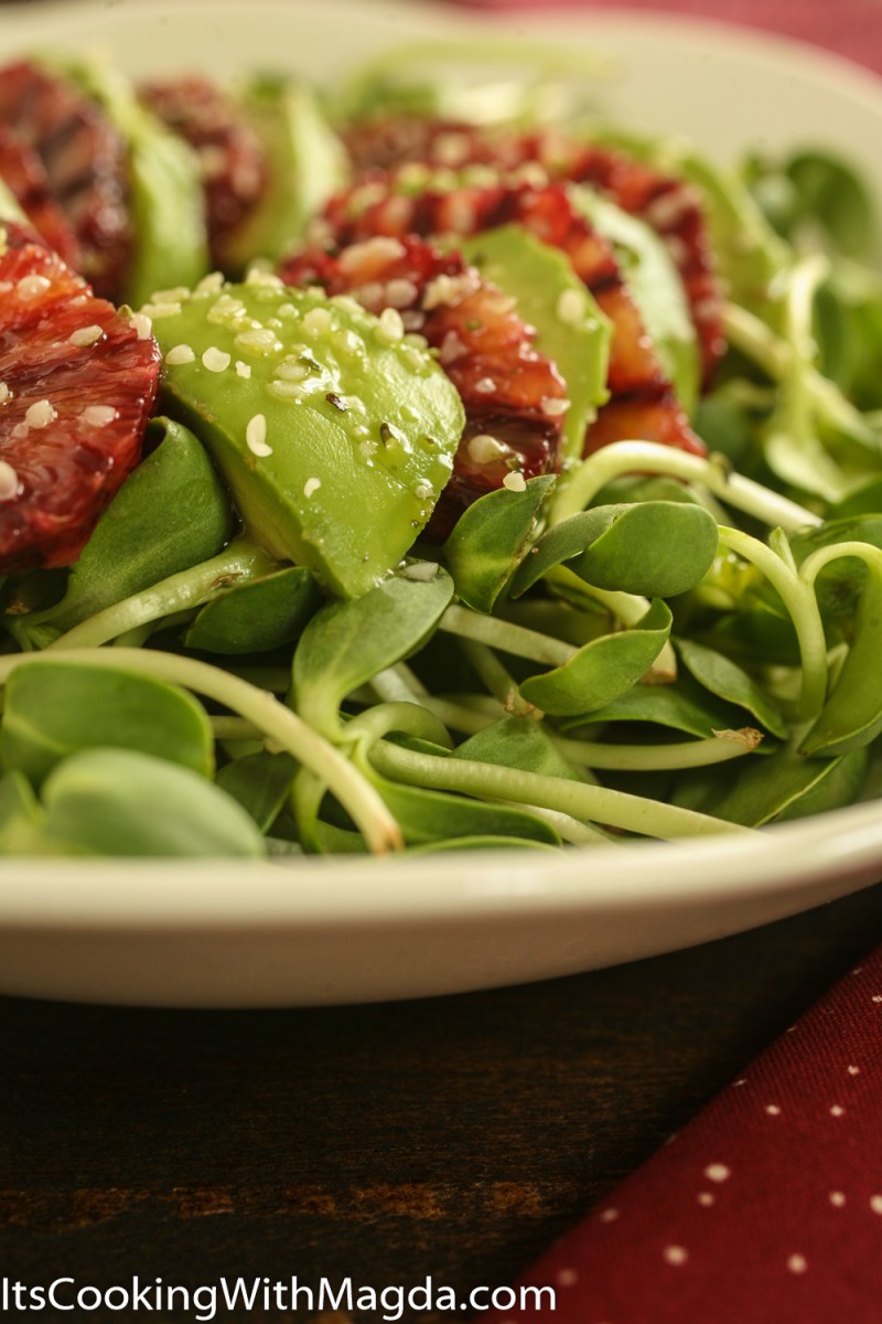 blood orange and avocado slices on top of a bed of greens