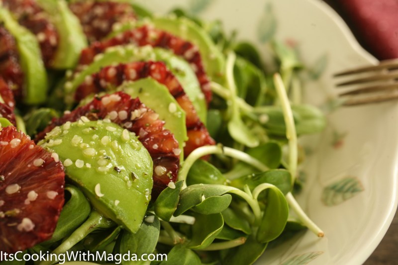 salad of sunflower shoots, avocado and orange on a plate