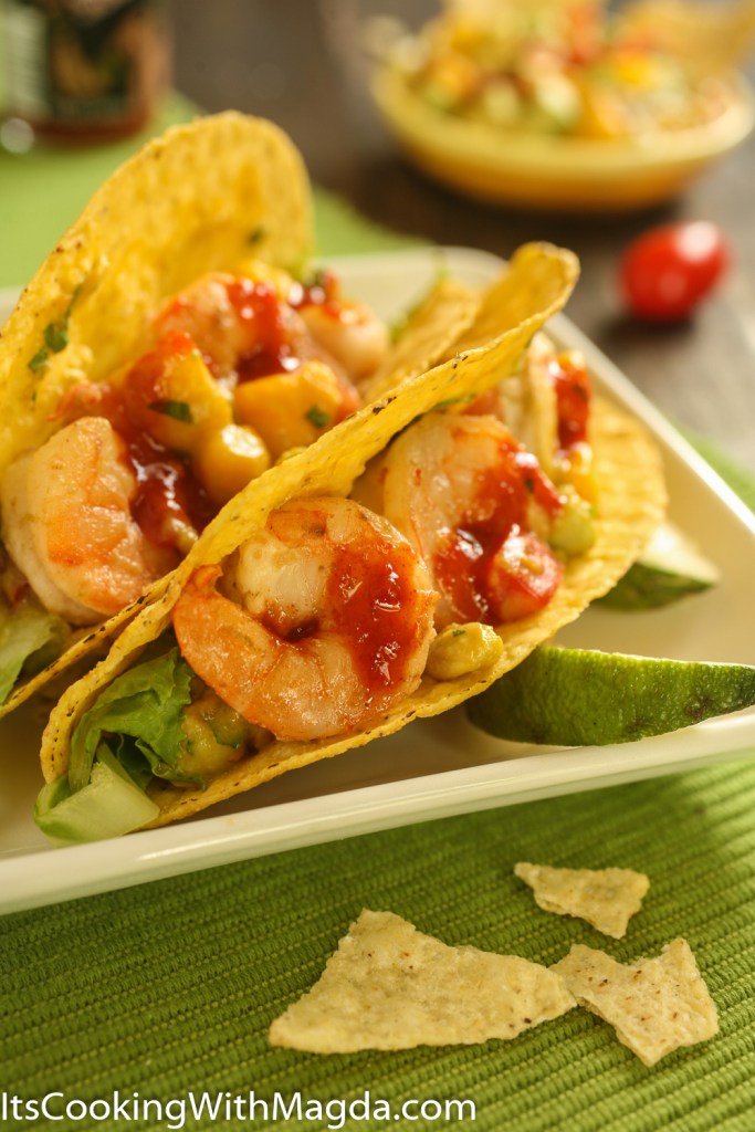 shrimp tacos with mango salsa in a crunchy taco shell with some hot sauce