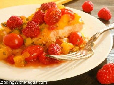a serving of oven baked salmon with mango salsa and fresh raspberries