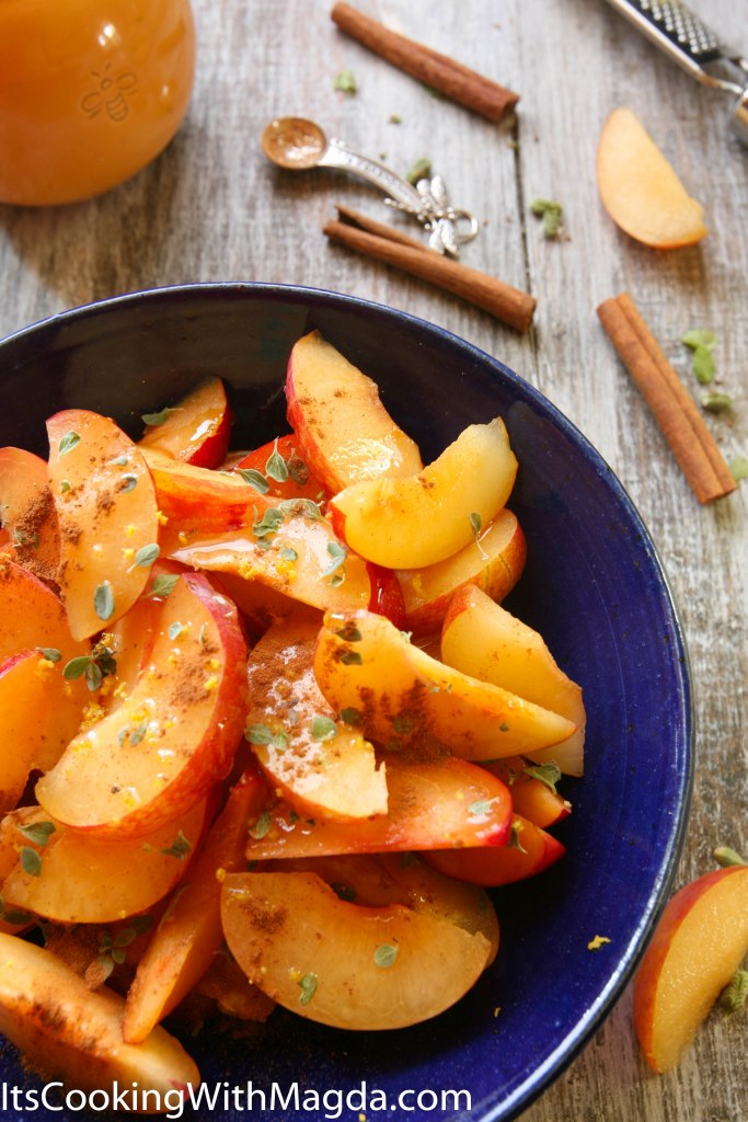 sliced plums in a blue bowl with spices and herbs