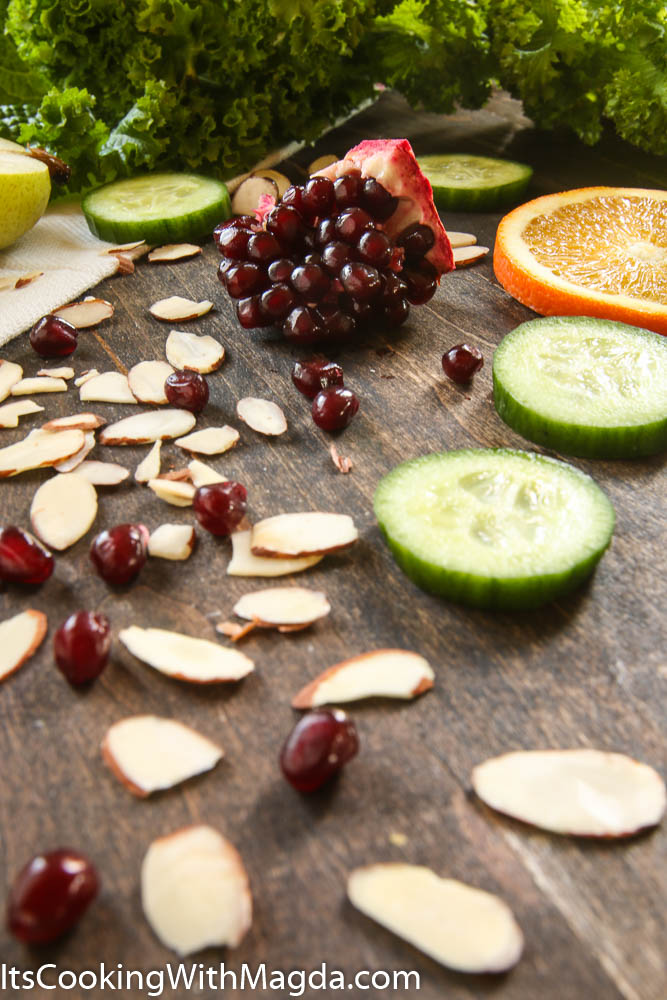pomegranate seeds, cucumber slices, almond flakes part of a mustard greens salad