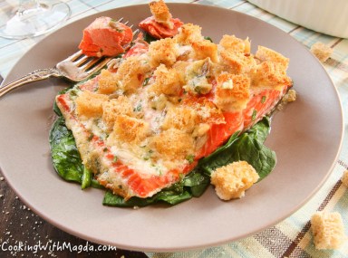 baked salmon with croutons on a bed of sauteed spinach